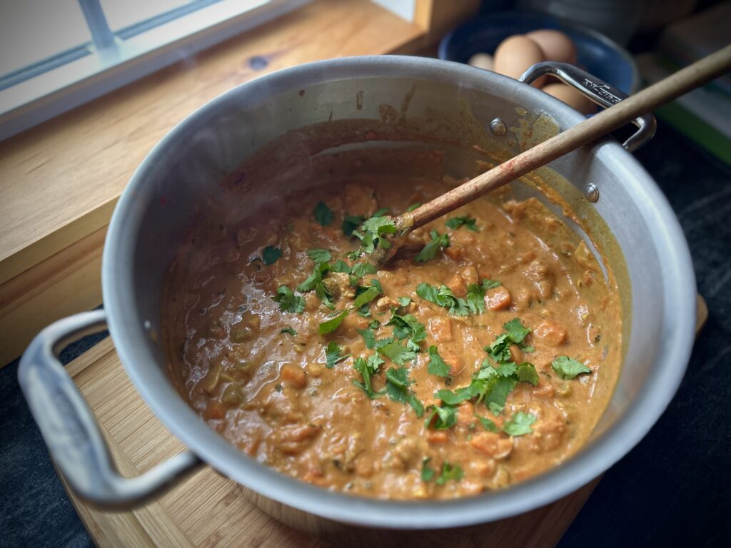 Senegalese-inspired peanut stew simmering in a pot topped with fresh cilantro.
