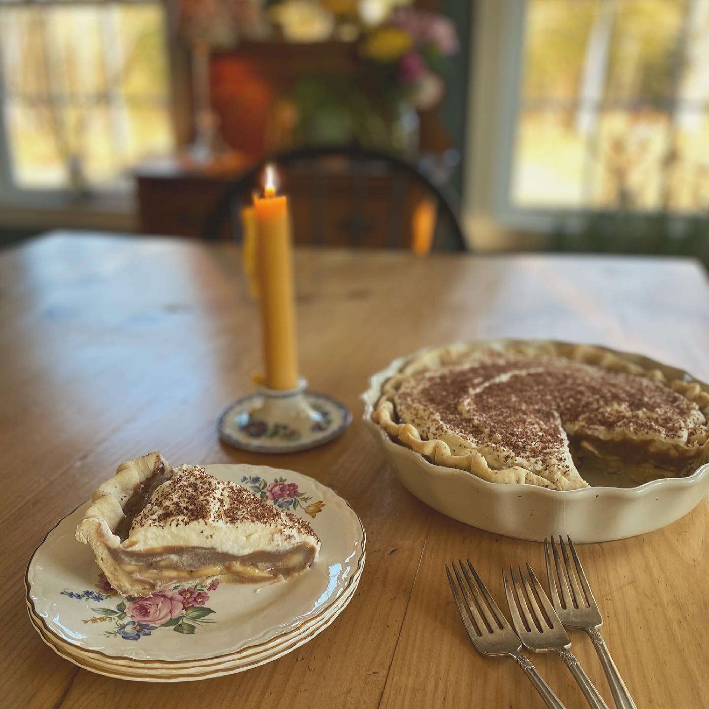 Chocolate banana cream pie slice with banana layers, whipped cream topping, and chocolate shavings on a farmhouse table