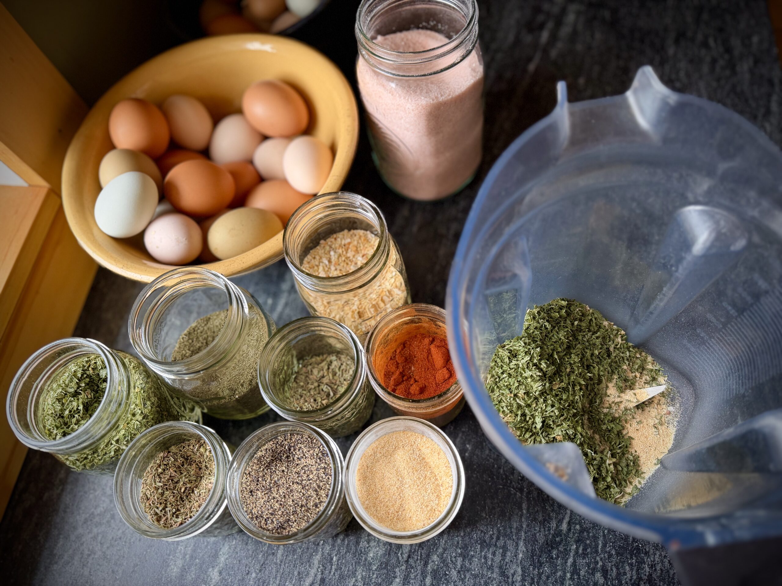 ingredients for homemade ranch seasoning mix in blender with jars of dried herbs