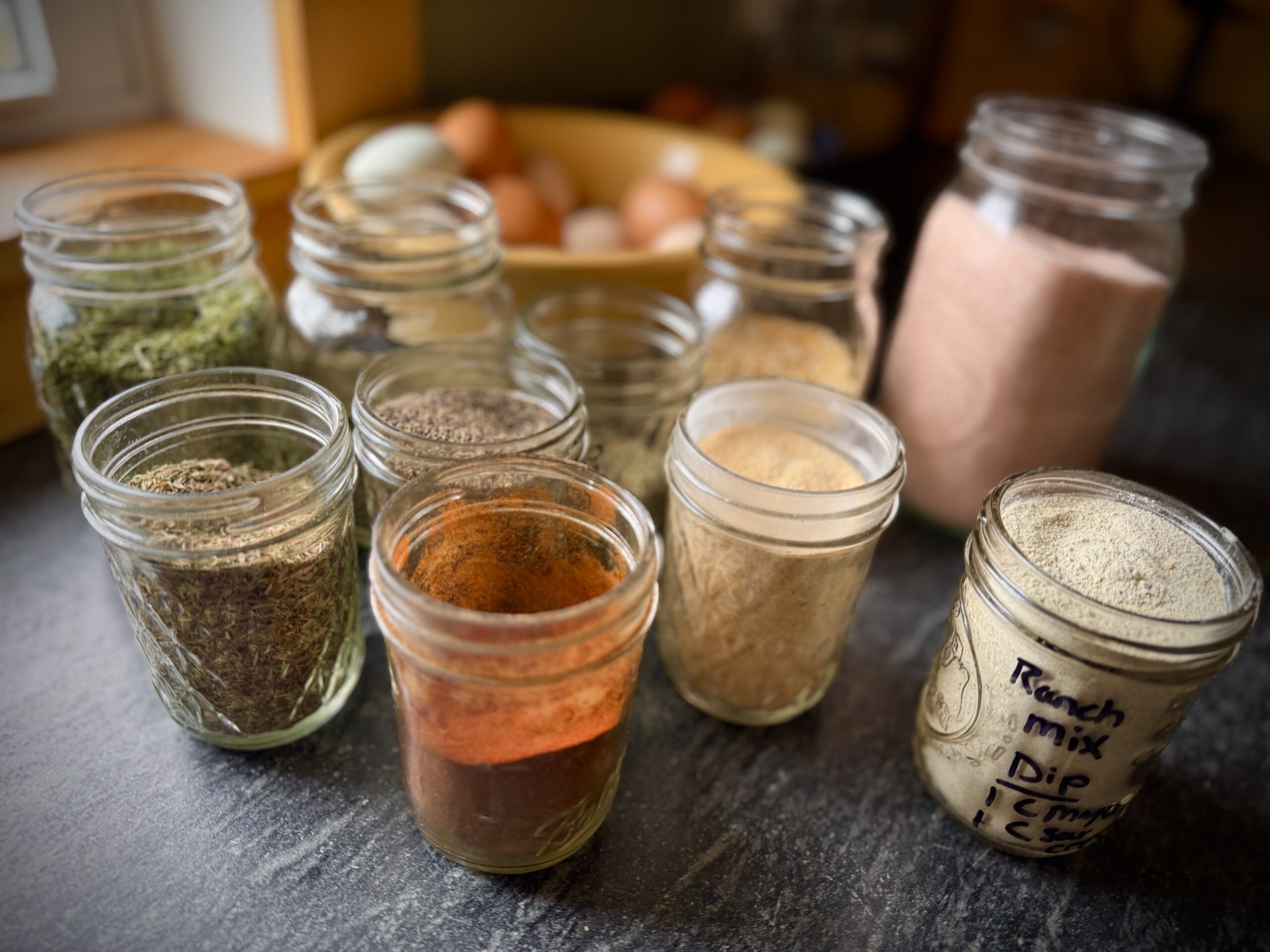homemade ranch seasoning mix ingredients in mason jars with dried herbs and spices