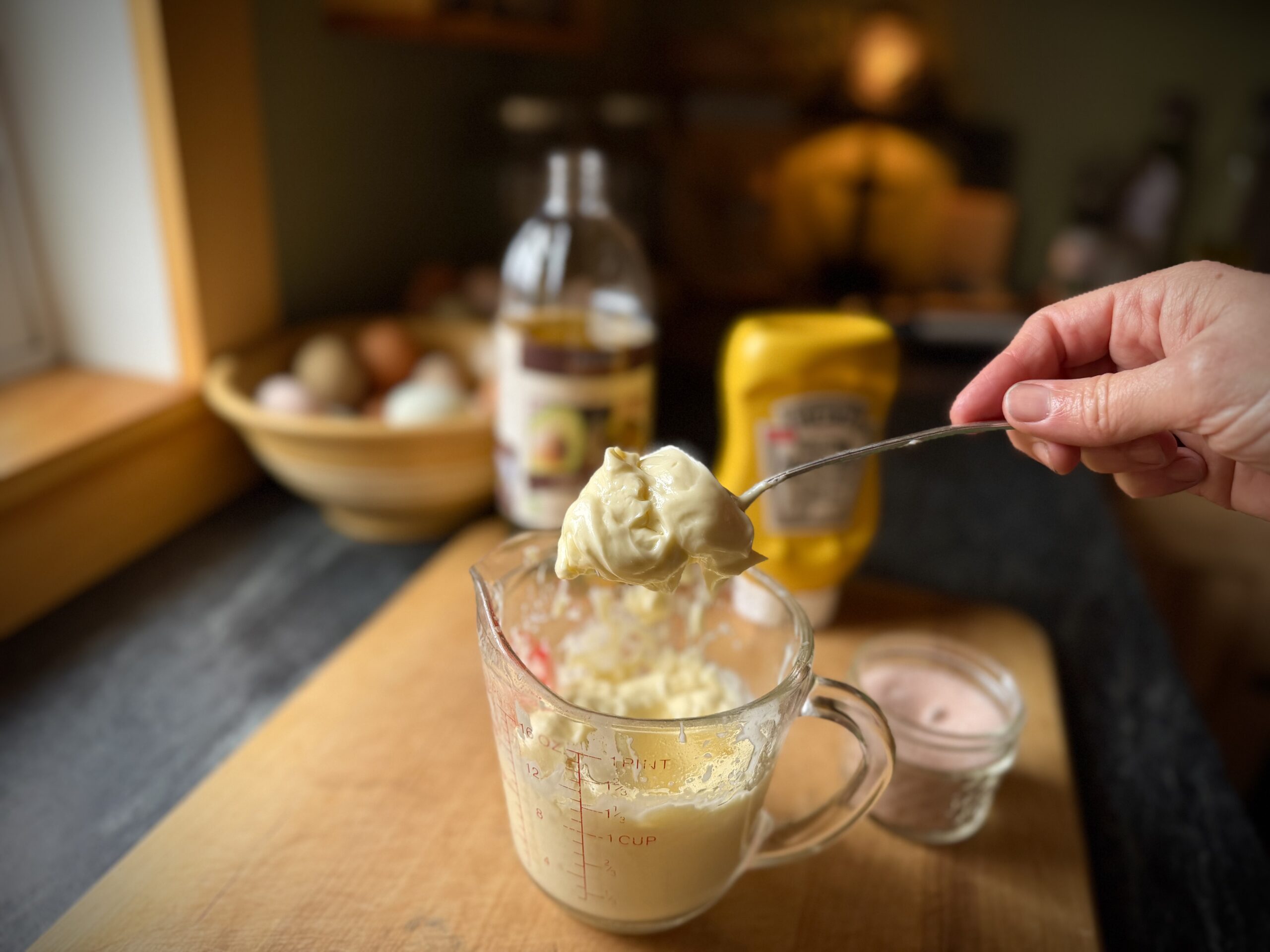 spoonful of homemade mayonnaise showing thick texture in measuring cup