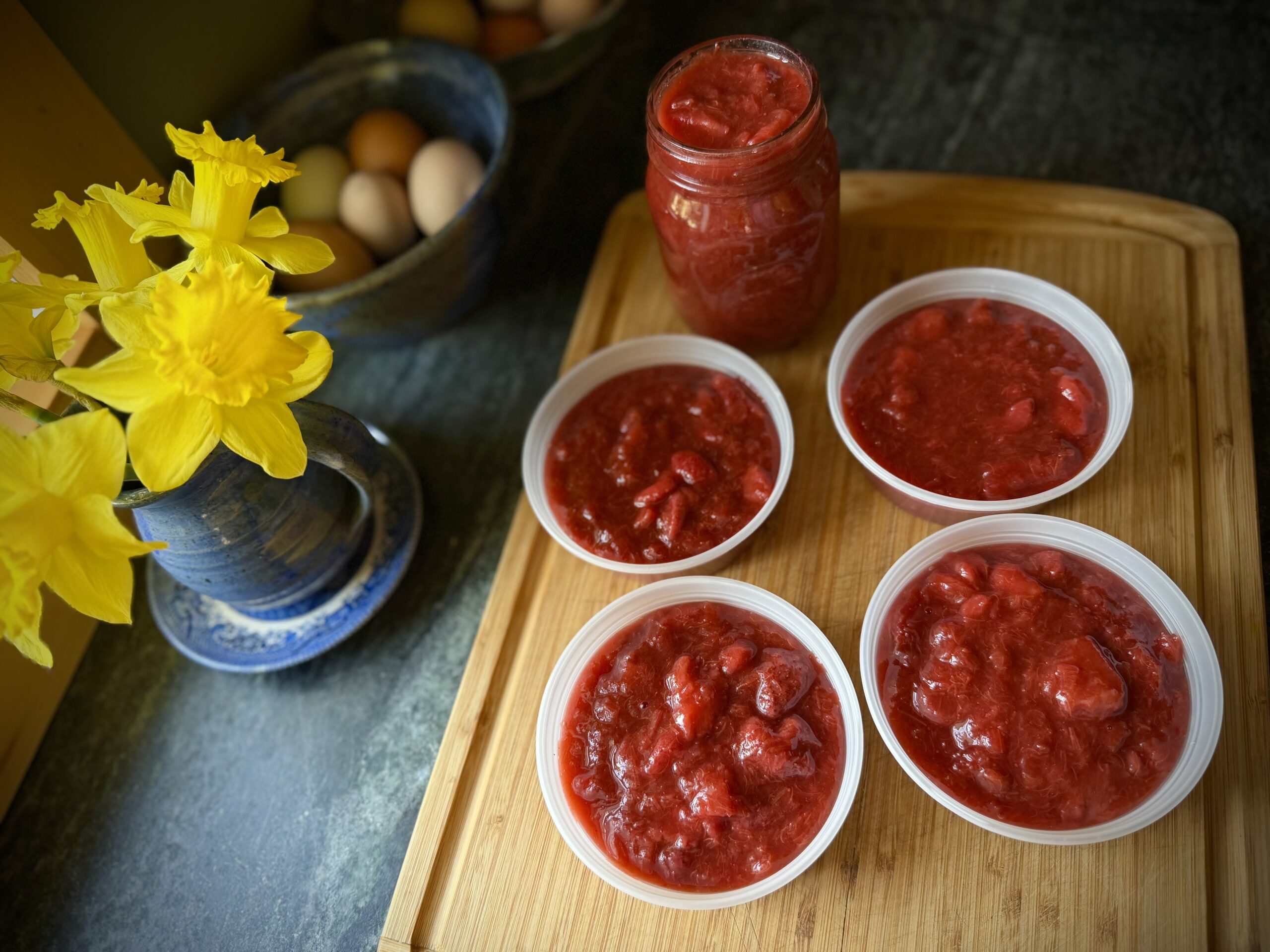 Strawberry rhubarb topping portioned into small containers on a wooden board