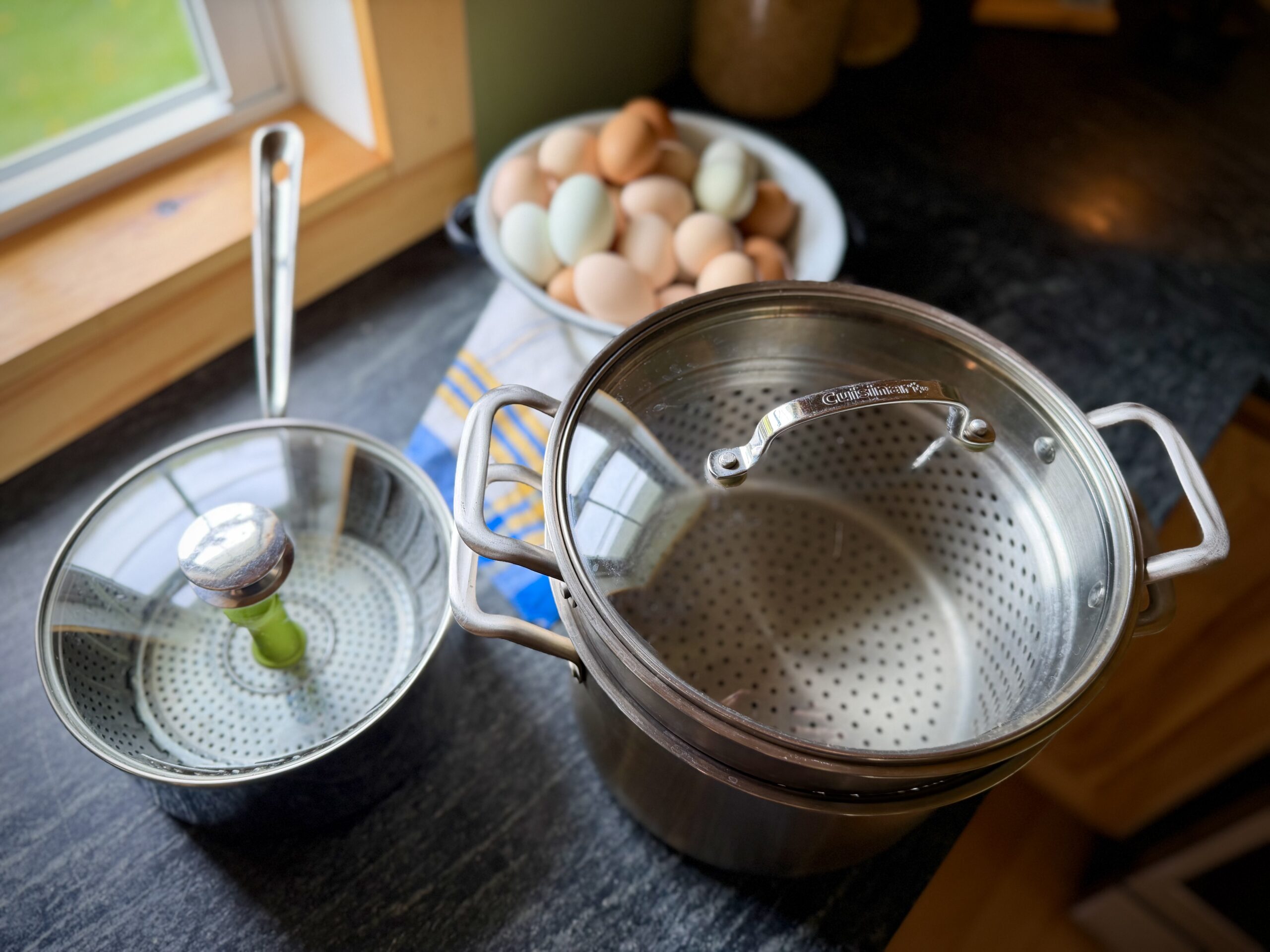 Stainless steel steamer pots and farm fresh eggs on a homestead kitchen counter for making easy-peel steamed hard boiled eggs