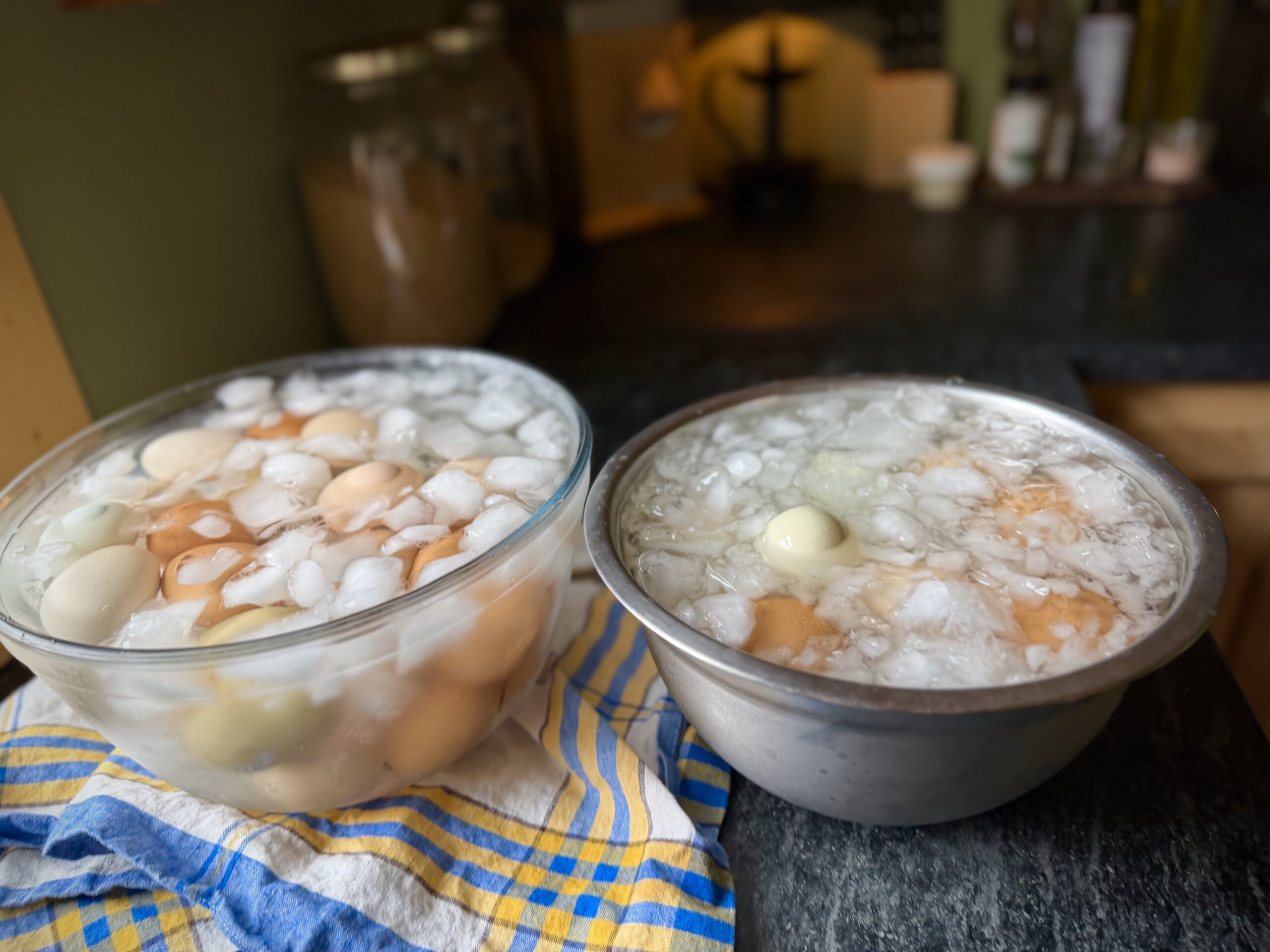 Hard boiled eggs cooling in large ice water baths after steaming for easy peeling
