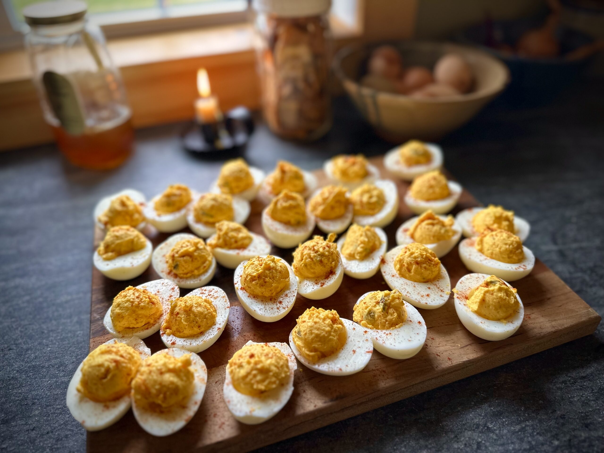 Classic homemade deviled eggs arranged on a wooden board in a cozy homestead kitchen