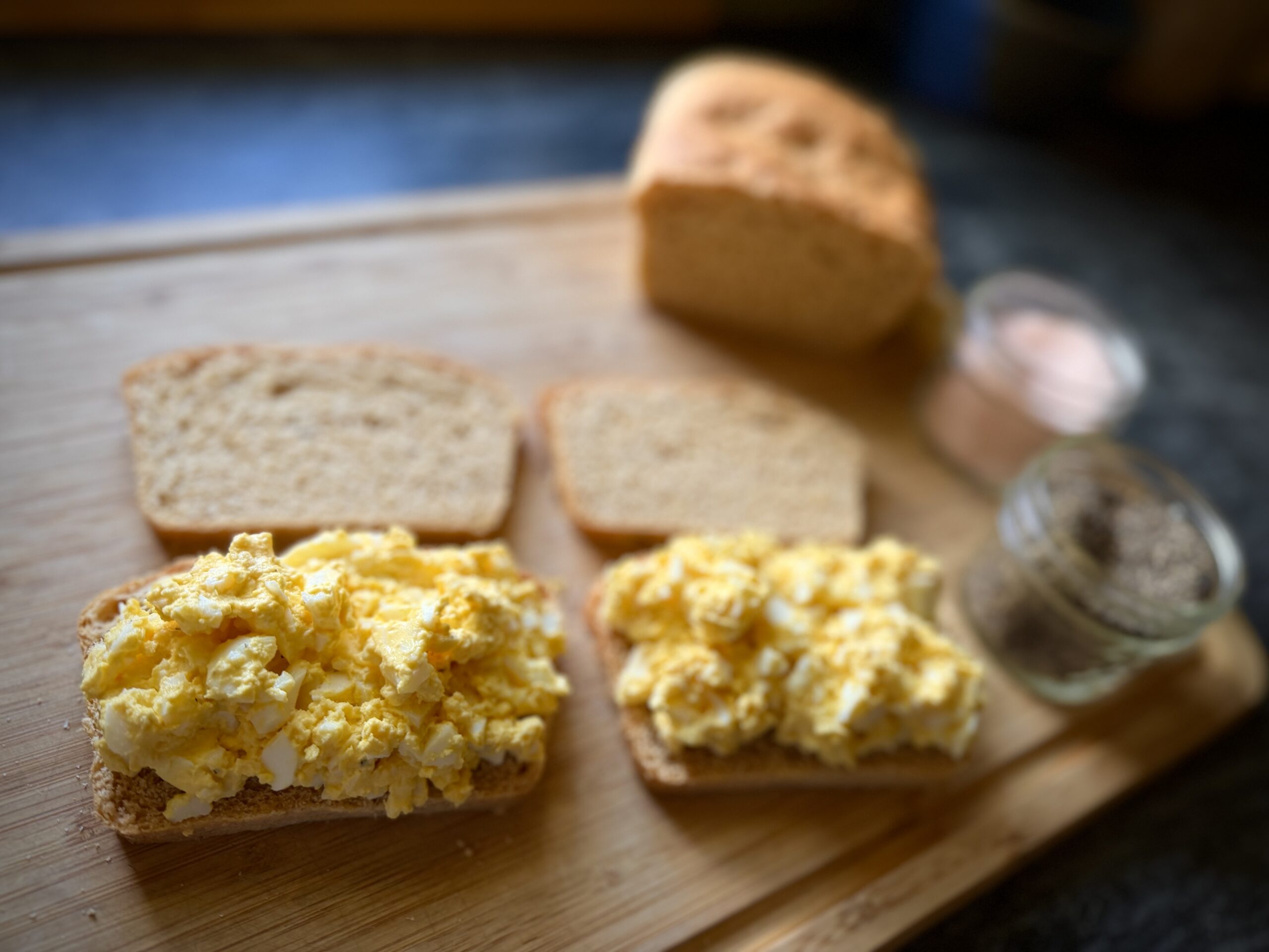 Open-faced egg salad sandwiches made with farm fresh eggs on homemade bread in a cozy homestead kitchen.