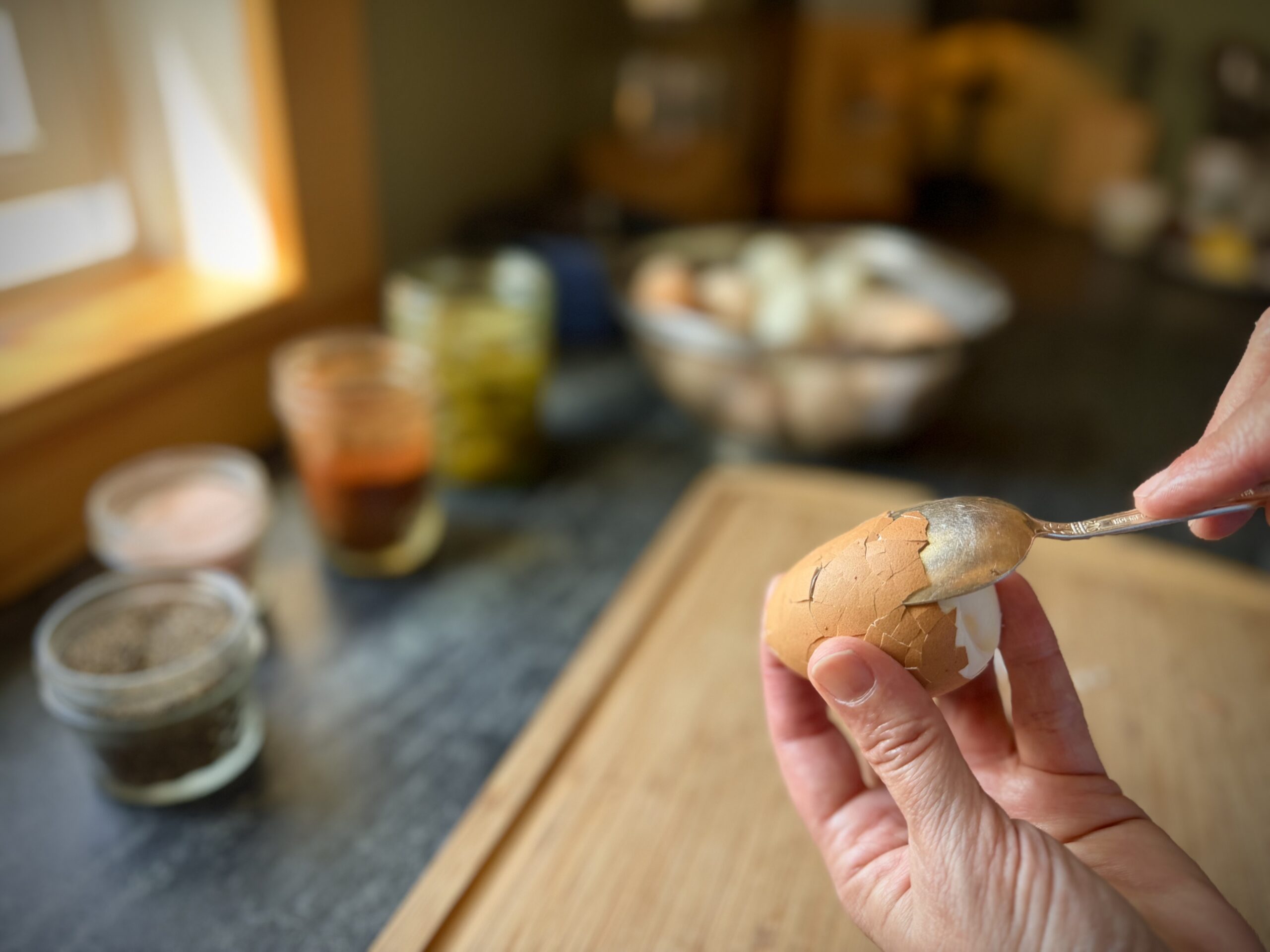 Using a spoon to loosen the shell of a steamed hard boiled egg for easier peeling