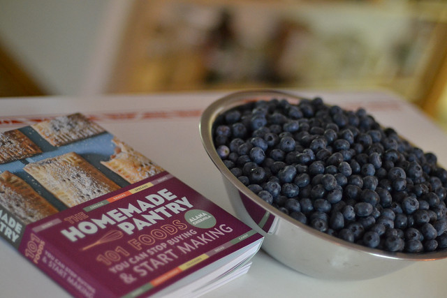 Blueberry glacé pie served with fresh blueberries beside a vintage cookbook.