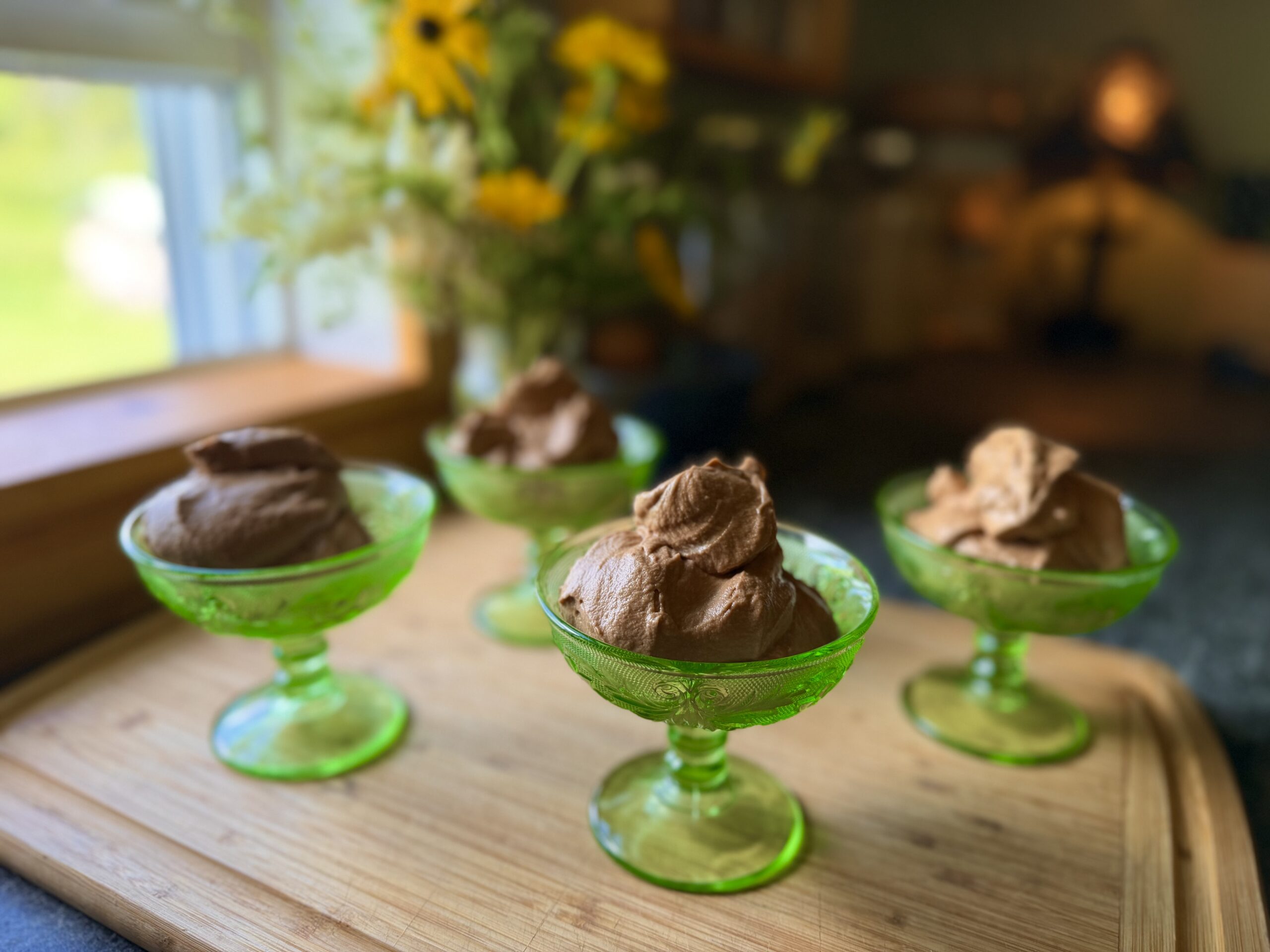 Homemade chocolate mousse served in vintage green dessert dishes on a wooden board.