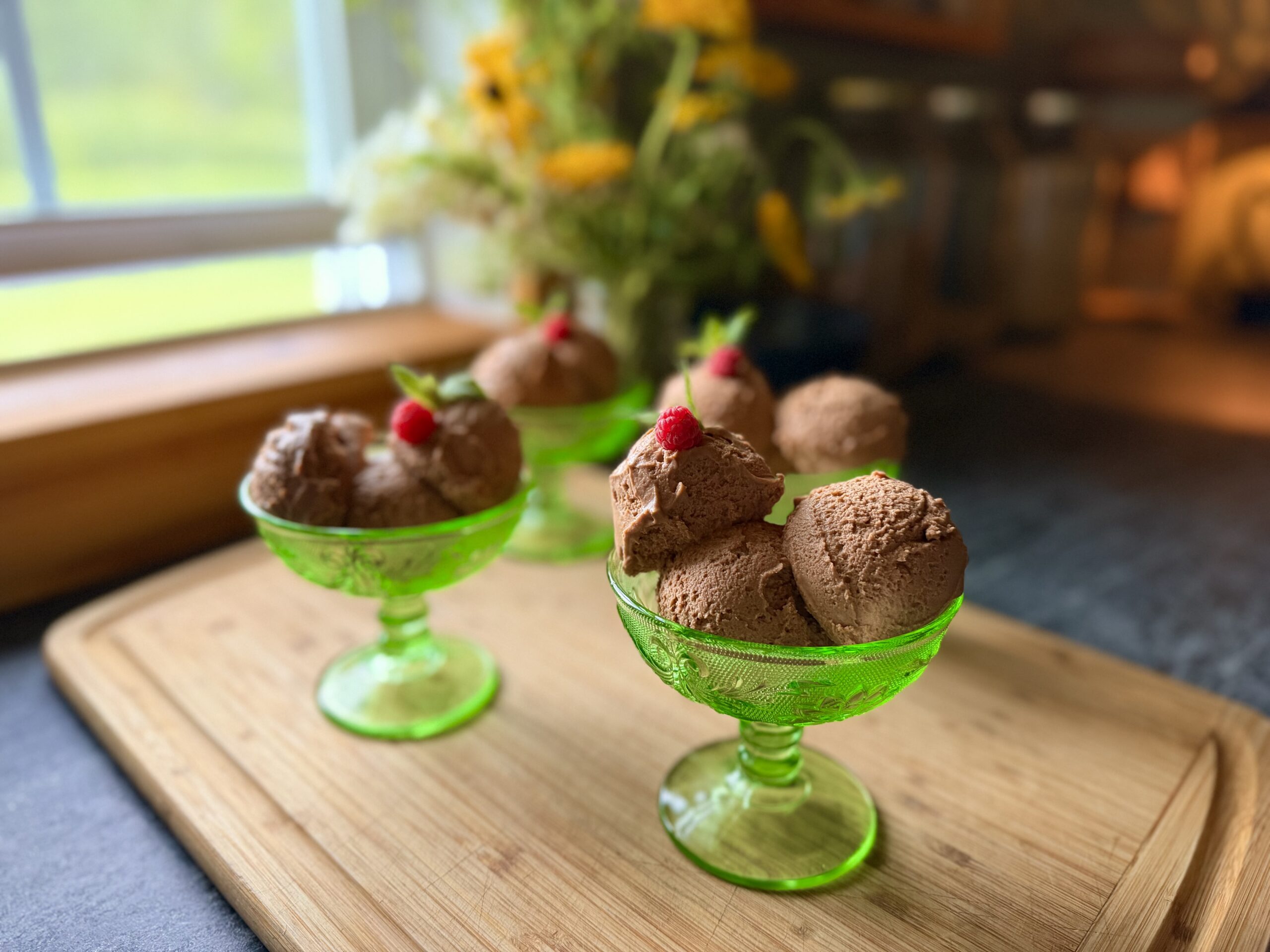 Chocolate mousse served in green glass dessert dishes with fresh raspberries and mint.