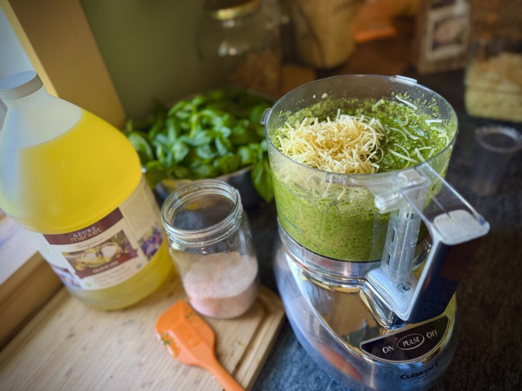 Freshly grated Parmesan cheese added to homemade basil pesto in a food processor before mixing.