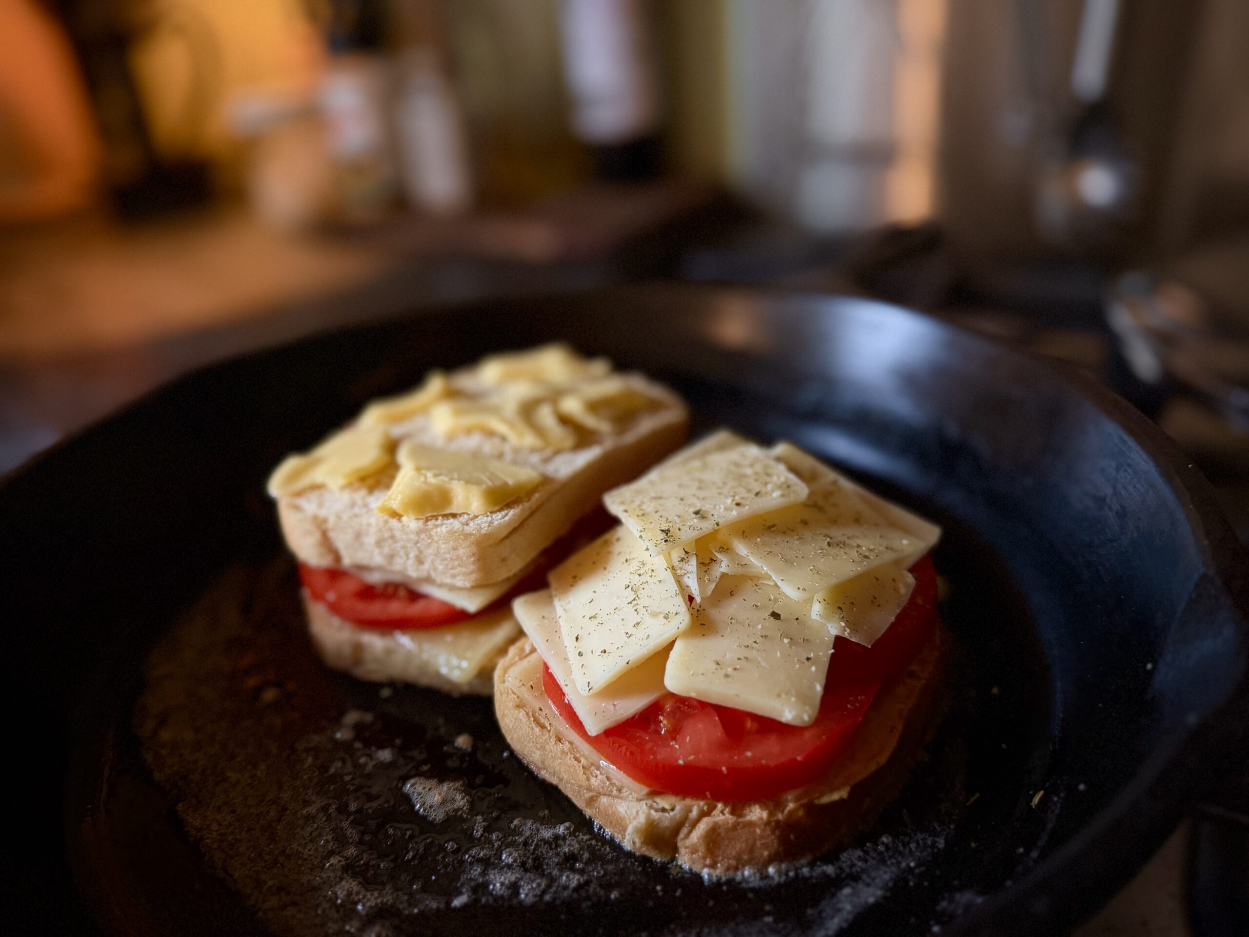 Tomato grilled cheese layered with cheddar and fresh tomato in a cast iron skillet