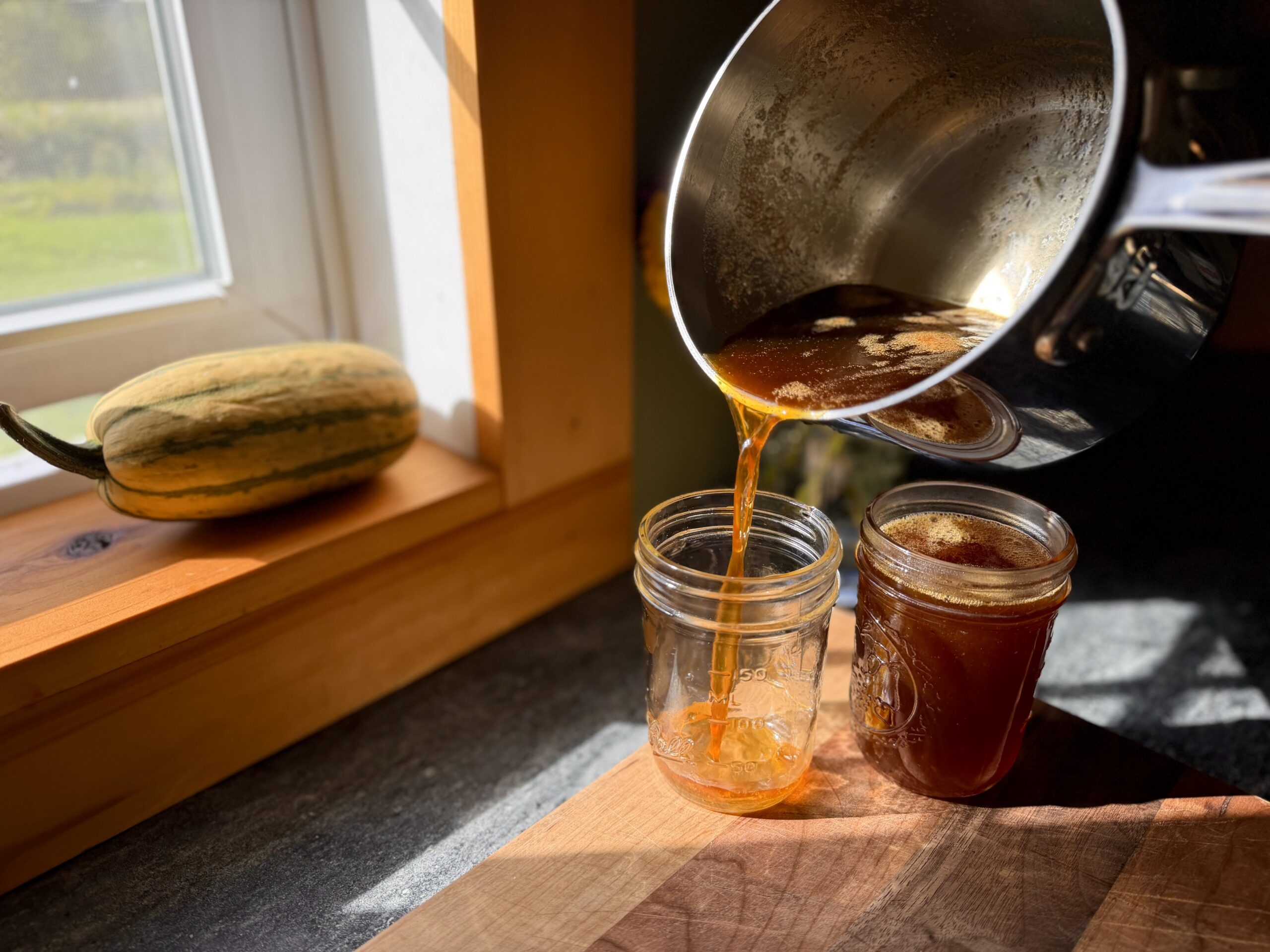 Homemade pumpkin spice maple syrup being poured into glass jars