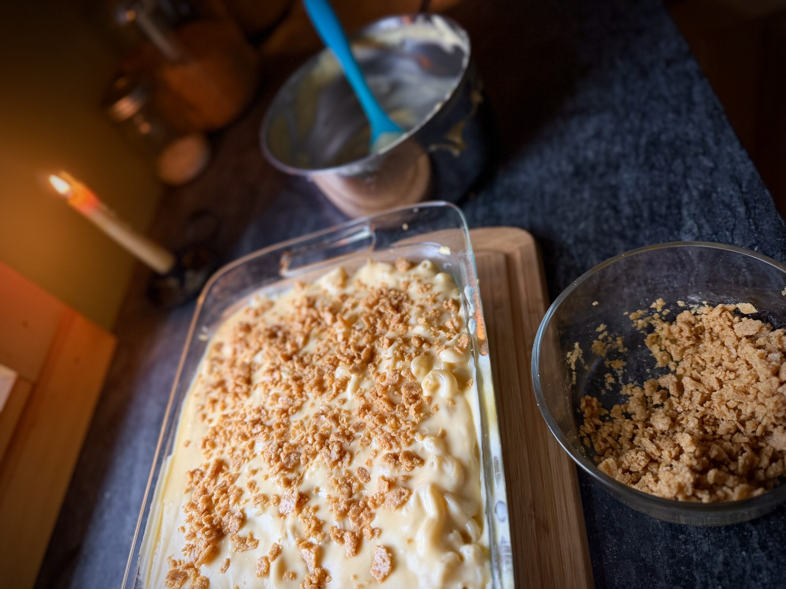 Crushed cracker topping being sprinkled over classic farmhouse macaroni and cheese before baking